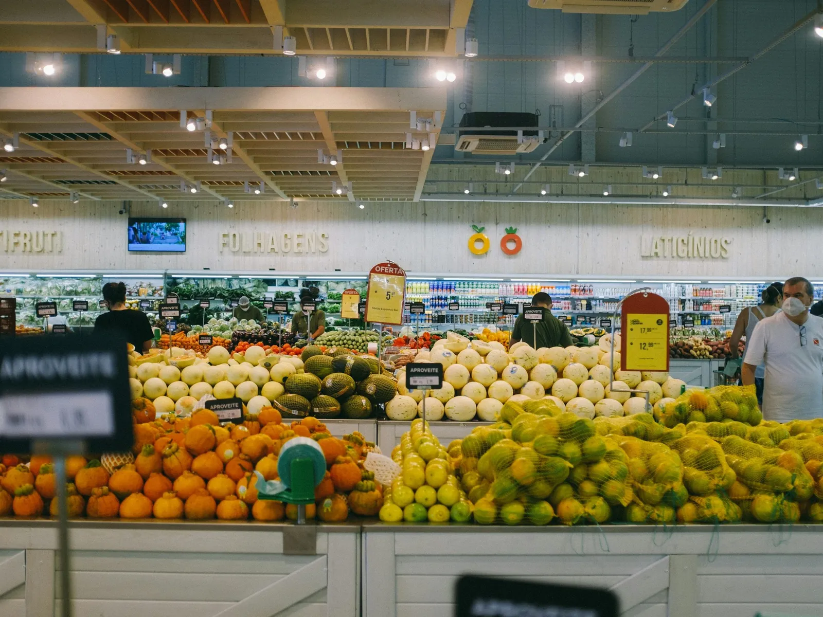 A bright supermarket produce floor with fruit stands